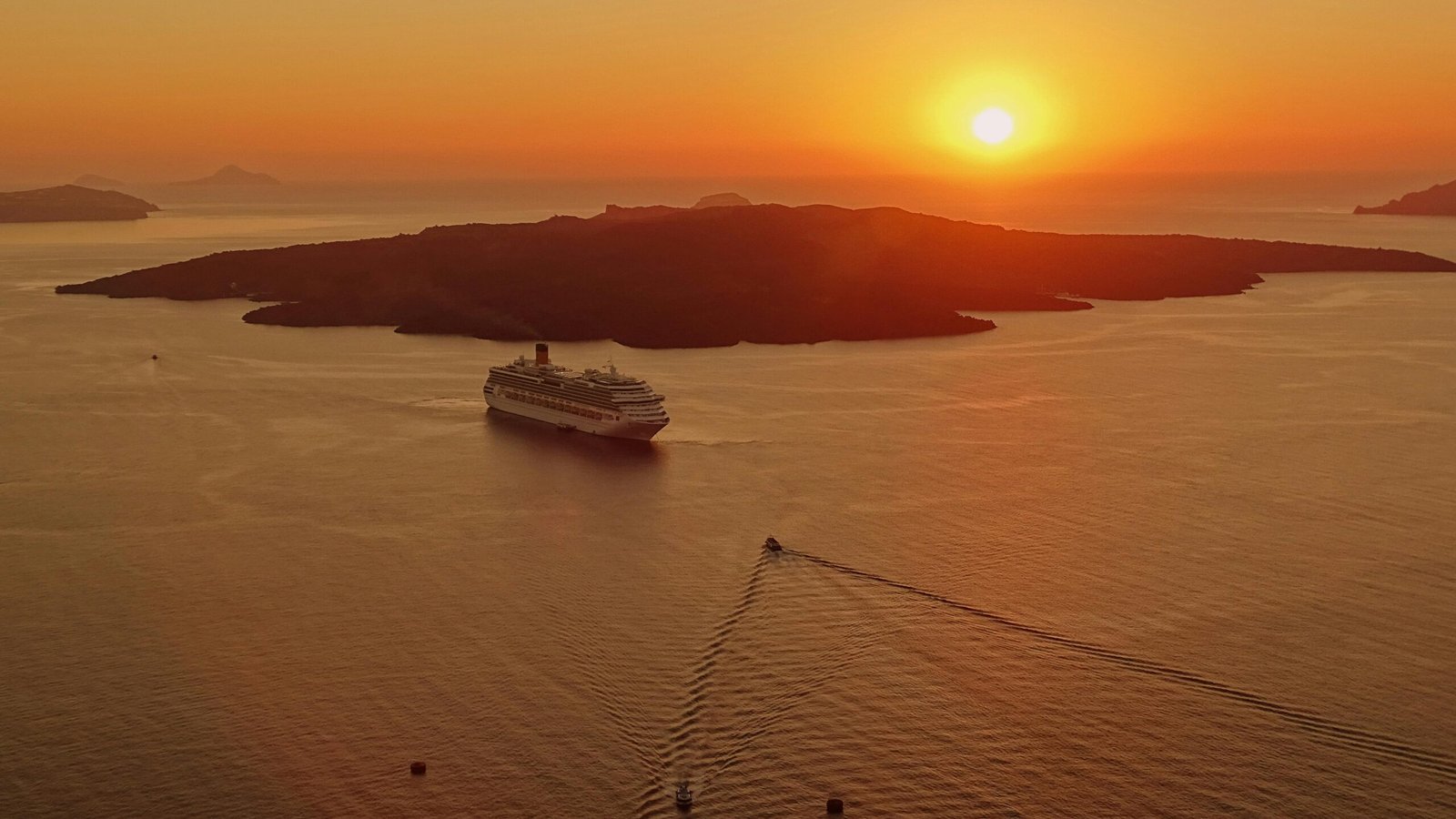 A breathtaking sunset view of a cruise ship near the island of Santorini, Greece.