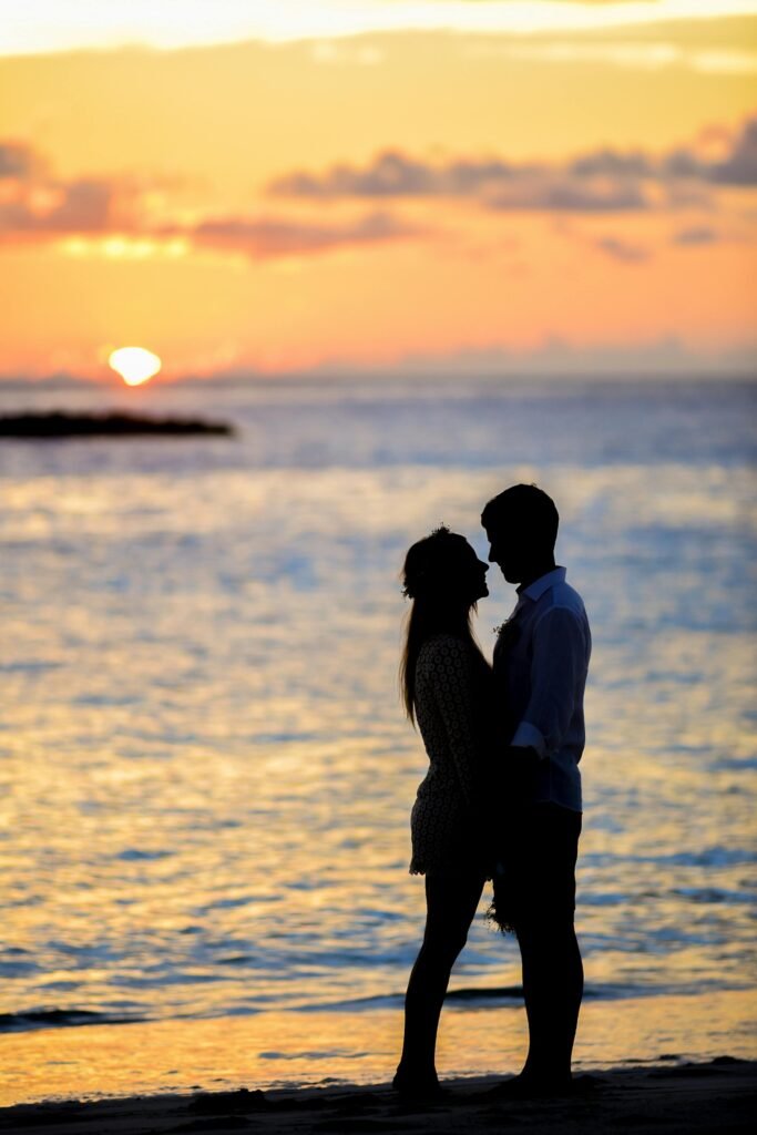 A couple sharing a romantic moment on a beach at sunset, creating a beautiful silhouette.