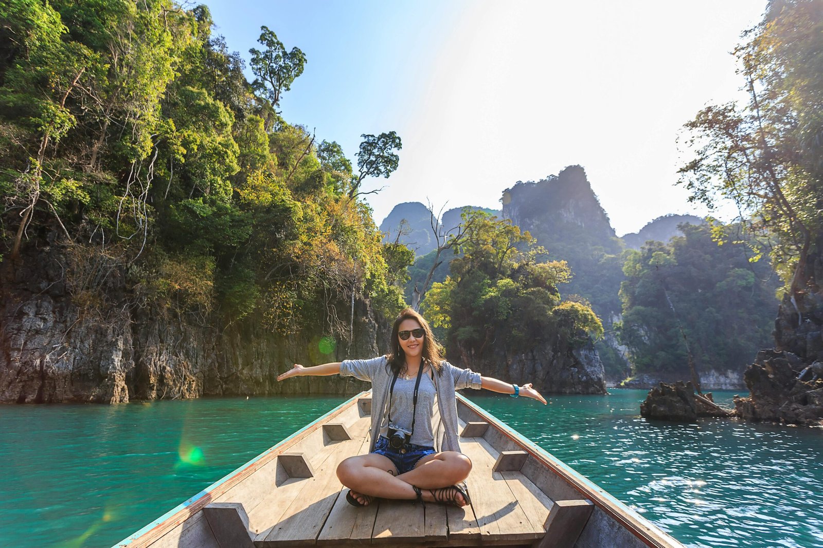 Asian woman relishing a serene boat journey through the lush karst landscape of Thailand's Khlong Sok.