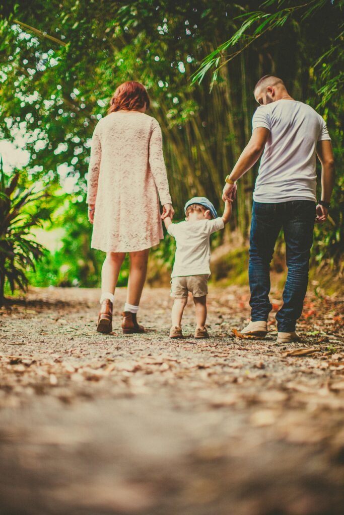 A family enjoys a leisurely walk in a green park, embodying joy and togetherness.